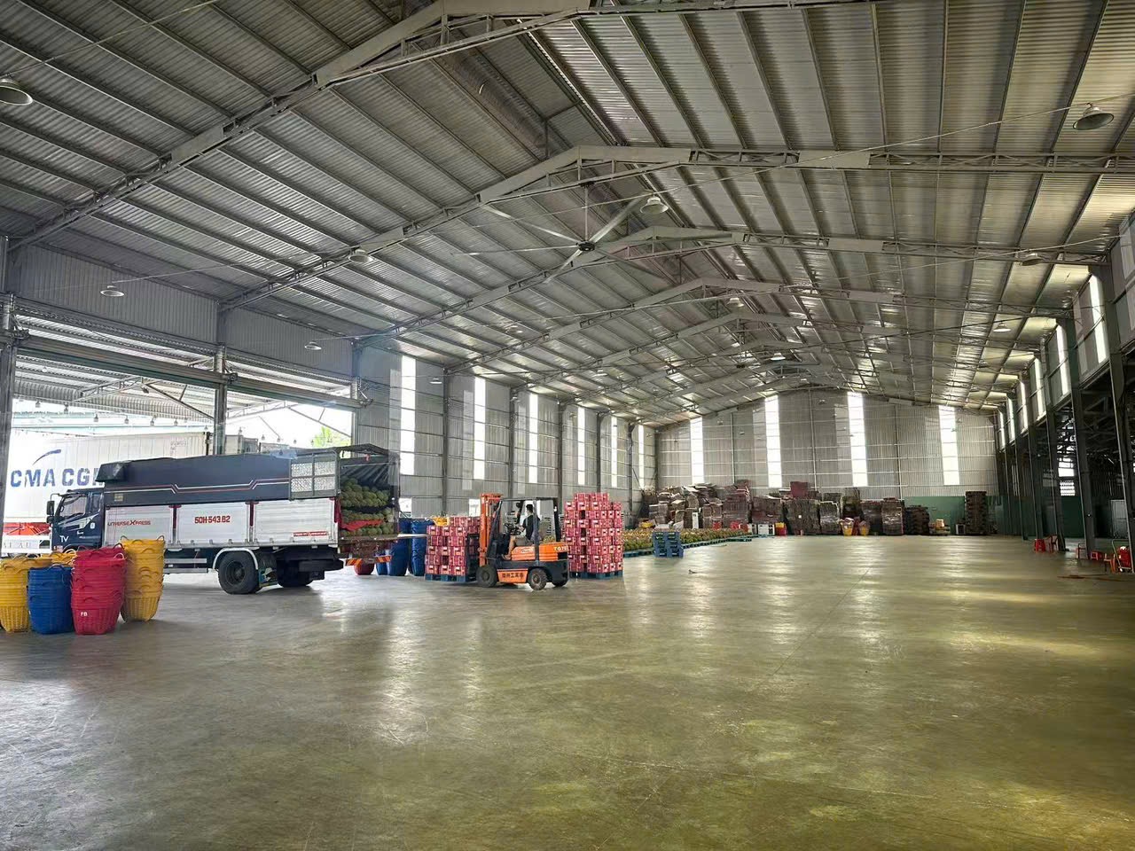 Không gian kho lớn với xe tải, xe nâng và hàng hóa